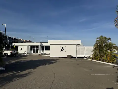 A commercial building with a white exterior beside a car park